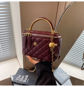 Detailed view of burgundy quilted leather chain bag with golden handle and ball buckle
