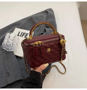 Detailansicht weinrote Stepptasche mit Goldblume und Doppelreißverschluss im Fokus