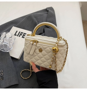 Detailansicht der cremefarbenen Stepptasche mit Goldblume und Metallgriff