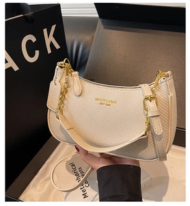 Détail du sac à bandoulière tissé beige avec chaîne dorée et emballage cadeau élégant