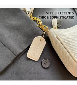 Detailed close-up of cream woven handbag texture with gold chain strap and leather tag