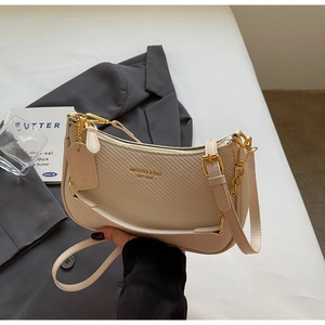 Close-up of beige woven texture bag with gold hardware and brand logo detail