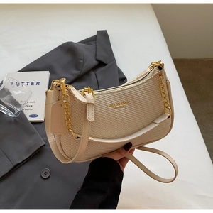 Close-up of woven texture cream crescent bag with gold chain and brand logo