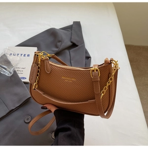 Close-up of brown woven texture shoulder bag with gold zipper and chain detailing
