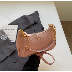 Detailed macro view of pink crescent bag with woven texture and gold metal chain