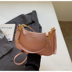 Close-up of pink crossbody bag texture with gold zipper and metal chain detail