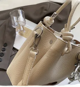 Close-up of litchi grain leather texture with silver metal hook and knot handle detail