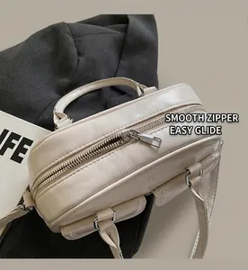 Detail of creamy white glossy wrinkled leather handbag with decorative buckled pockets