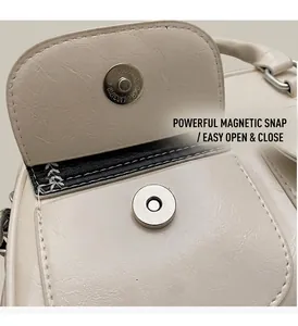 Macro shot of the magnetic snap closure on a cream faux leather pillow handbag