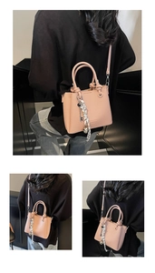 Macro detail of salmon pink textured leather bag with silk scarf and metal charms
