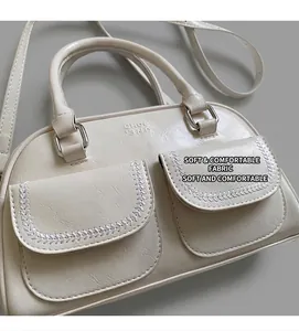 Detail of cream white leather handbag featuring woven stitching and double front pockets