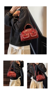 Close-up of red glossy leather handbag with white stitching and detachable shoulder strap