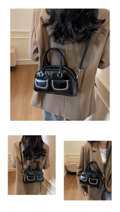 Detailed view of black Boston bag featuring contrast white stitching and dual front pockets
