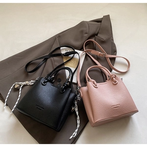 Detail of mini bucket bags in black and pink litchi grain leather with woven rope charm
