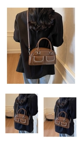 Detail of dark brown boston bag with white stitching and two front flap pockets