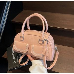 Detail of pink PU leather Boston bag with white stitching and silver hardware on stairs