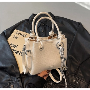 Détail du sac seau en cuir crème avec poignée nouée épaisse et décoration en corde tissée