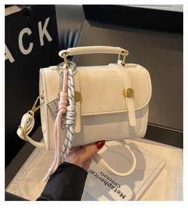 Detail of cream crossbody bag featuring matte suede flap and unique abacus charm