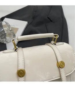 Dettaglio borsa beige vintage opaca con finiture dorate e manico superiore cilindrico
