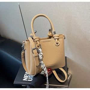 Vue détaillée du sac seau en cuir litchi beige avec pendentif clochette en argent