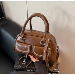 Detailed view of a brown vintage leather shoulder bag with white contrast stitching