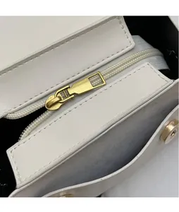 Dettaglio macro della cerniera in metallo dorato lucido su borsa in pelle bianca