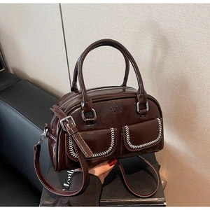 Detail of dark brown leather handbag with white baseball stitching and logo