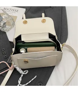 Dettaglio della borsa a tracolla bianco crema che mostra l'interno spazioso e la chiusura magnetica