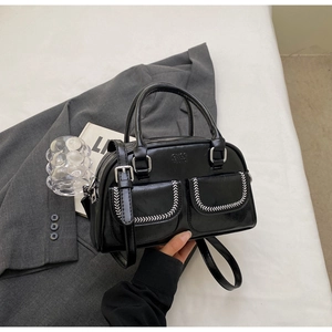 Close-up of black PU handbag showing double front pockets with white V-stitching details