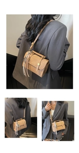 Detail view of khaki crossbody bag with vintage gold button and braided tassel charm accessory