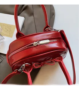 Detail of red wax leather handbag with glossy finish, metal zippers and bow accent