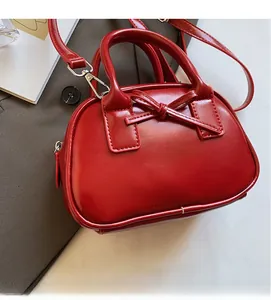 Detail of red leather bowling bag featuring a delicate bow and silver metal hardware