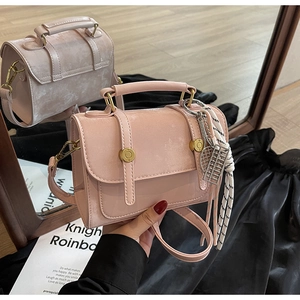 Detail view of pink glossy handbag featuring gold hardware and mirror reflection style