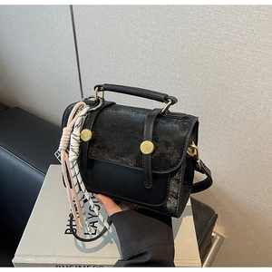 Dettaglio borsa a tracolla in pelle nera vintage con fibbie dorate e ciondolo intrecciato