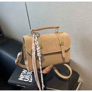 Dettaglio borsa beige-marrone con inserti opachi e chiusura a cilindro in metallo oro