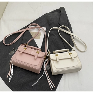 Detail of vintage matte crossbody bags in pink and cream with woven tassels and gold hardware