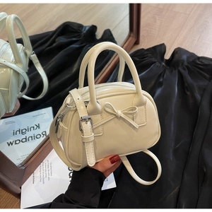 Detail of cream white mini bowling bag with bow decoration and adjustable strap