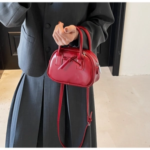 Detail of red bow-knot handbag featuring silver hardware and a smooth faux leather finish