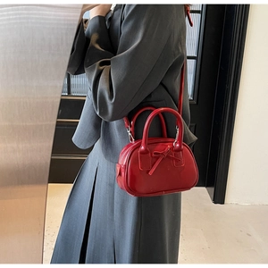 Detail of red patent leather bowling bag with bow decoration and dual top handles