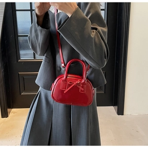 Glossy red mini bowling bag with bow detail held by model in a stylish outfit