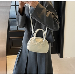 Detail of cream-white bow handbag with crossbody strap shown on grey suit outfit