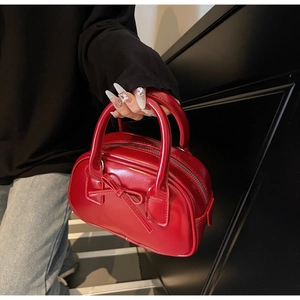 Close-up of red glossy patent leather bowling bag with bow detail and metal zipper