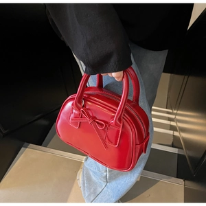 Close-up of a mini red patent leather bowling bag featuring a stylish bow and top handles
