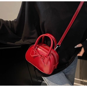 Detail of red bow-knot Boston bag with silver hardware and detachable crossbody strap