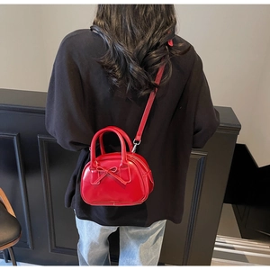 Chic red bow handbag with crossbody strap shown on black outfit for size reference