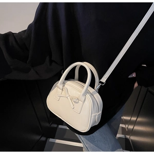 Detail of cream leather handbag with 3D bow and adjustable shoulder strap on model