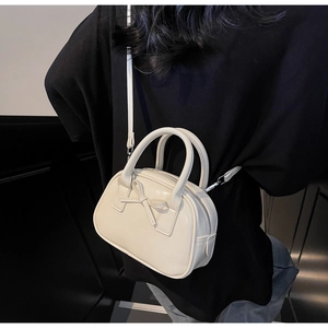 Detail of a beige bow-decorated bowling bag showing its sleek PU leather texture and strap