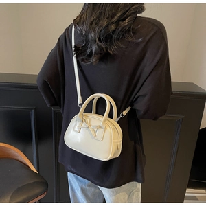 Detail of cream crossbody bag with bow accent and detachable strap shown on model
