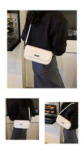 Detail of a creamy white baguette shoulder bag with a silver metal turn-lock closure