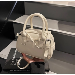 Close-up of a creamy white bow handbag with silver hardware and detachable strap